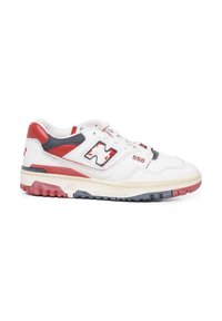Zapatilla de piel blanca con acentos en rojo y marino, detalle perforado y suela de goma texturizada. Presenta un diseño con cordones y logotipos en contraste.