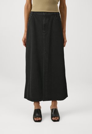 Black denim maxi skirt with a straight cut, high waist, front seam detailing, and side pockets. Paired with open-toe black mules.