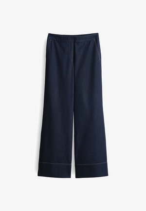 Weite, dunkelblaue Jeanshose mit weicher Textur, elastischem Bund, seitlichen Taschen und kontrastierendem Stich am Saum.