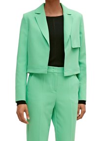 Miętowa, zielona, krótka marynarka wykonana z teksturowanej tkaniny, z kołnierzem z wycięciami oraz kieszenią z klapką z przodu, w zestawie z dopasowanymi, szytymi na miarę spodniami.