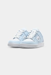 Šviesiai mėlyni odiniai sportbačiai su baltais akcentais, apvaliu pirštu, perforuota apdaila ir baltais raišteliais. Lacoste logotipas šoniniame šone. Lygus guminis padas.