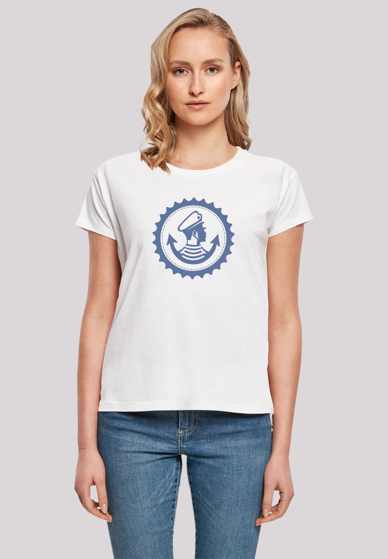 Weißes Baumwoll-T-Shirt mit einem blauen grafischen Design eines Matrosenkopfes innerhalb eines kreisförmigen Anker-Motivs, kurzen Ärmeln und einem lockeren Schnitt.