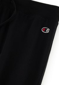 Schwarze Sweatpants aus weichem Material, mit einem elastischen Bund und Kordelzug sowie einem kleinen gestickten Logo in Rot und Weiß.