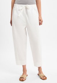 Weiße Baumwollhosen mit elastischem Bund und Kordelzug, mit lockerer Passform und verkürzter Länge. Getragen mit beigen flachen Sandalen.