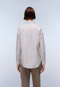 Striped long-sleeve shirt in light beige and white. Features a pointed collar and buttoned cuffs with a straight-cut back design.
