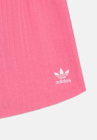 Rosa ribbet tekstil med horisontale linjer, med en hvit Adidas-logo nederst til venstre.