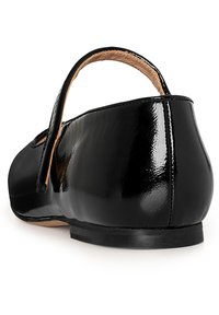 Zapato de charol negro con tacón bajo y correa en el tobillo. Acabado suave y brillante con punta redondeada y detalles de costura mínimos.