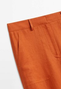 Oranje linnen broeken met een platte tailleband, twee zijzakken en verticale plooien. Gladde structuur met een natuurlijke vezel uitstraling.
