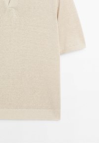 Beige neulepaita lyhythihainen V-aukkoinen malli, jossa on ribattu helma. Pehmeä rakenne, sileä pinta ja rento istuvuus.