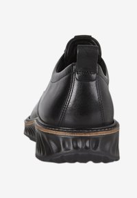 Scarpe in pelle nera con punta arrotondata, dettagli cuciti e suola in gomma testurizzata e rigata con un accento marrone in contrasto.