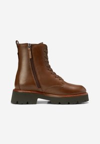 Bottines en cuir marron avec fermeture éclair et système de laçage. Semelle épaisse en caoutchouc vert, col rembourré et détail de couture latérale.