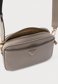 Borsa a tracolla in similpelle grigia con ferrature color oro, doppio scomparto con zip e una targhetta triangolare con logo sul davanti.