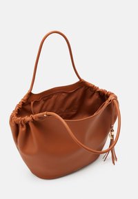 Borsa a tracolla in pelle marrone con cima morbida e arricciata, manico singolo e accentatura con nappina. L'interno spazioso dispone di una tasca con zip.