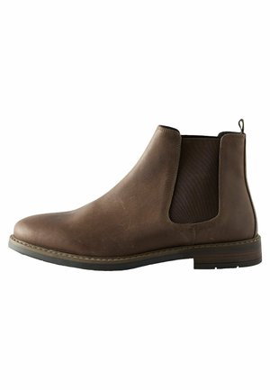 Botín Chelsea de cuero marrón con paneles laterales elásticos, punta redondeada, tacón bajo y una lengüeta en la parte trasera. Textura suave con un veteado sutil.