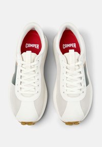 Sneakers bianchi con texture in rete e liscia, con una soletta rossa etichettata "CAMPER" e un sottile accento verde di lato.
