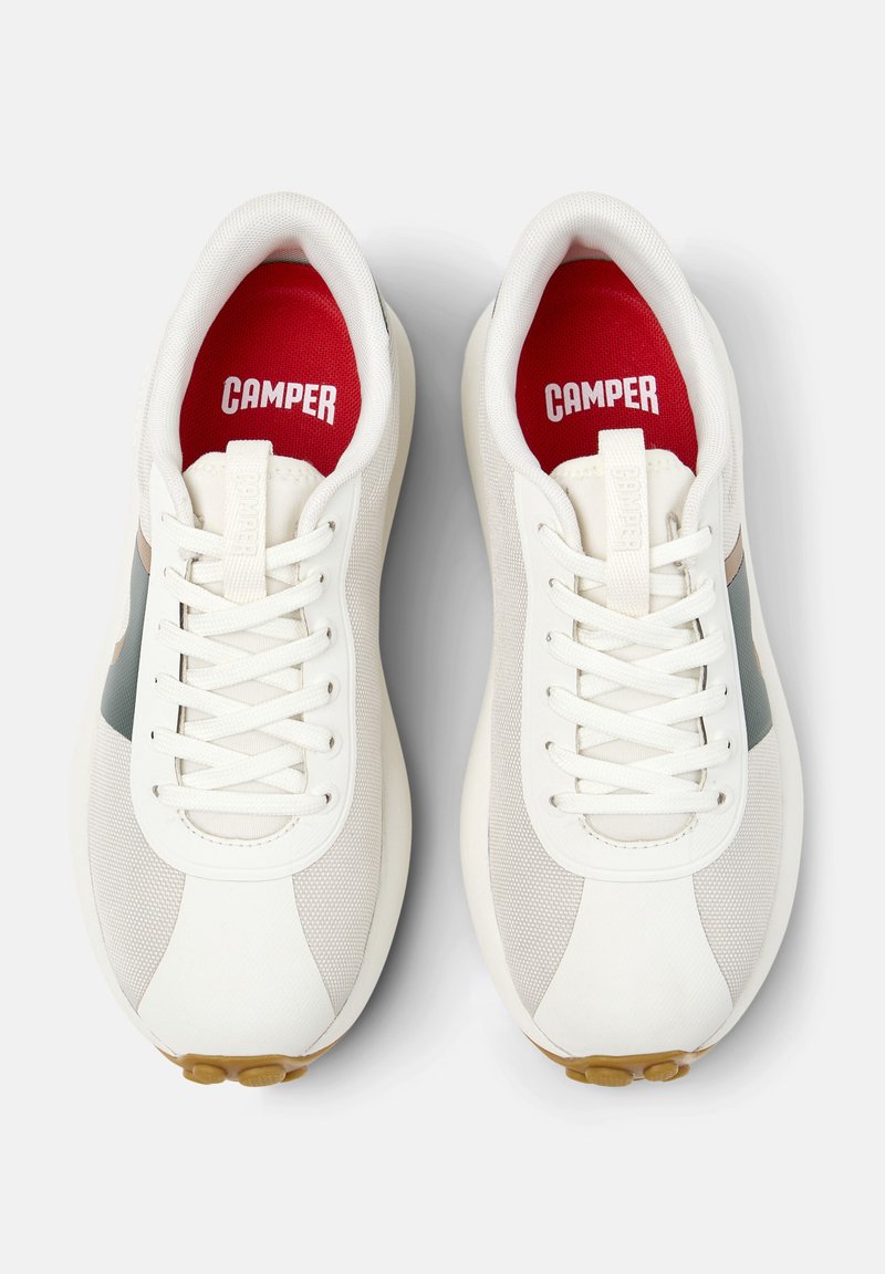 Weiße Sneakers mit Netz- und glatten Texturen, einer roten Innensohle mit der Aufschrift "CAMPER" und einem subtilen grünen Akzent an der Seite.