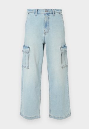 Vaaleansiniset farkku-cargo-housut, joissa on leveät lahkeet, kaksi sivutaskua, nappikiinnitys ja hieman haalistunut pinta.