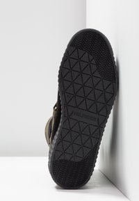 Semelle de chaussure en caoutchouc noir avec un motif de grip texturé, arborant le nom de marque "HILFIGER" en relief, offrant durabilité et traction.