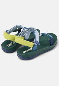 Grüne Sandalen mit verstellbaren Riemen in Hellblau und Gelb. Sie verfügen über eine Polsterung und eine strukturierte Sohle mit dem "CAMPER"-Logo in Weiß.