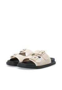 Beige vävda sandaler med dubbla justerbara remmar, detaljer i guld och en svart gummisula. Öppen tån-design med texturerad ovandel.