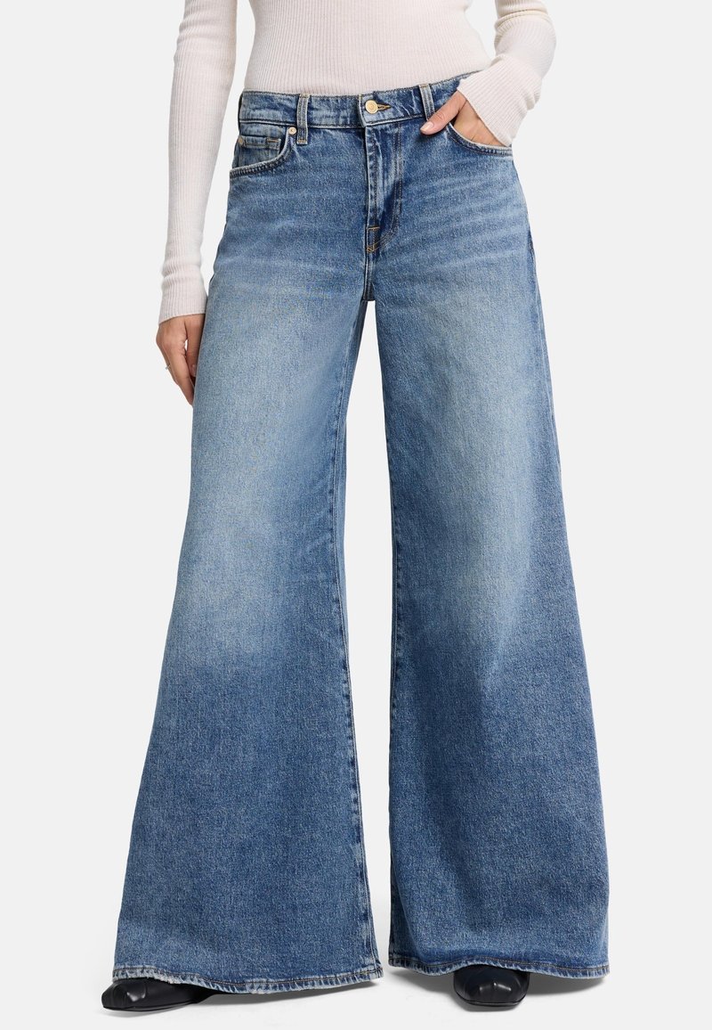 Laakehousut vaaleansinisestä denimestä, joissa on etutaskut, nappisuljenta ja haalistunut pesu sileällä pinnalla.