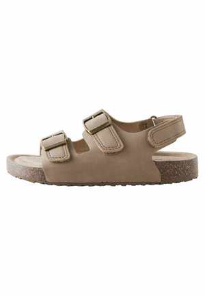 Beige Wildledersandale mit zwei verstellbaren Schnallen, offener Ferse und strukturiertem Korkmittelsohle. Flache Gummisohle für Grip und Komfort.