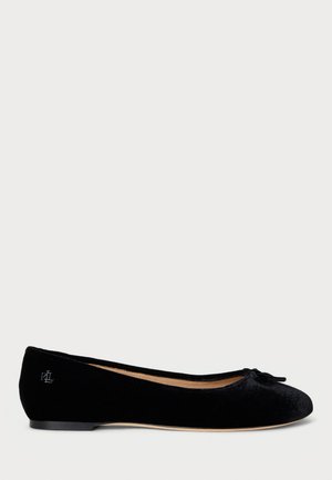Black velvet ballet flat with rounded toe, small bow on front, logo detail on heel, and flat sole.