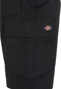 Pantaloni cargo neri realizzati in tessuto resistente, con molteplici tasche, cuciture rinforzate e un'etichetta del marchio tessuta sul lato.