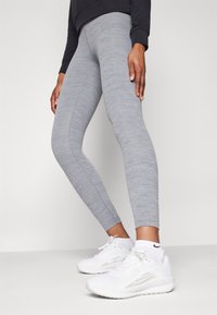 Sive legice iz raztegljivega materiala s heather vzorcem, v kombinaciji z belimi športnimi čevlji z diskretnim logotipom.