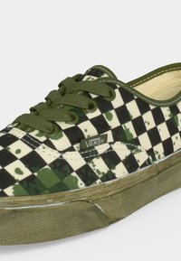 Αθλητικό Vans με πράσινα κορδόνια, πράσινο και κρεμ καρό μοτίβο, πράσινες πιτσιλιές μπογιάς και πράσινη λαστιχένια σόλα, σε πλευρική όψη.