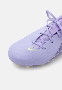 Scarpa da calcio di colore viola chiaro con un design elegante, superficie testurizzata e logo Nike giallo. Presenta una chiusura con lacci e tacchetti stampati sulla suola.