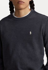 Marinblå crewneck sweatshirt i bomullsblandning, med ribbad krage och cuffs, samt en liten broderad logotyp på vänster bröst.