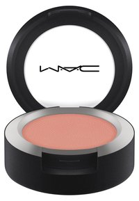 Compact blush in een ronde, matte zwarte doos met een zilveren rand. Bevat een getextureerde, zachte roze poeder van binnen. Logo zichtbaar op de deksel.