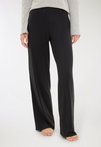 Pantaloni neri fluidi con una comoda cintura elastica, realizzati in materiale morbido e leggero. Presentano un taglio dritto e non hanno motivi visibili.