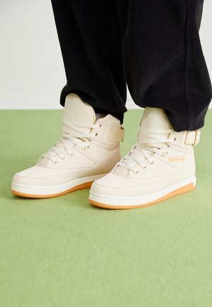 Beige High-Top-Sneaker mit glattem Leder außen, weißen Schnürsenkeln und orangen Gummisohlen. Verfügt über einen verstellbaren Riemen und strukturierte Akzente.