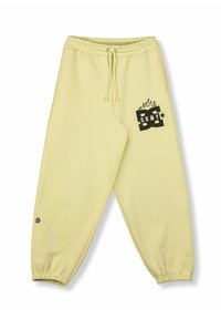 Pantalones de chándal amarillos claros con cintura y puños elásticos, bolsillos frontales y un logotipo gráfico negro con llamas en el muslo derecho y en el tobillo.
