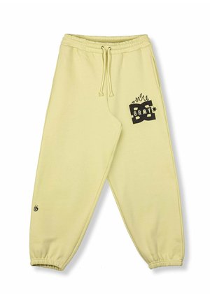 Pantaloni da jogging giallo chiaro con vita e polsini elasticizzati, tasche frontali e logo grafico nero con fiamme sulla coscia destra e sulla caviglia.