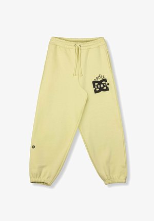 Lichtgele trainingsbroek met elastische taille en boorden, voorzakken en een zwart grafisch logo met vlammen op het rechterdijbeen en enkel.