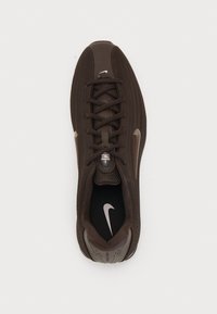 Tamnosmeđi atletski tenisice s mrežastim gornjištem, okruglim vrhom i ravnim vezicama. Sadrži Nike logo sa strane i teksturiranu vanjsku podlogu.