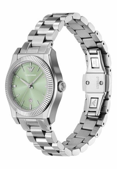 Silverfärgad klocka i rostfritt stål med grön urtavla, ribbad bezel, tre visare, datumbeskrivning och länkband.