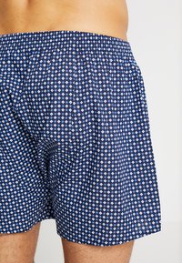 Mörkblå kalsonger med ett mönster som har små vita och ljusblå diamanter. Elastisk midja, lätt material, knä-lång klippning.