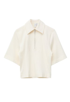 Polo crema a maniche corte con mezza cerniera argento sul davanti e colletto a punta, mostrata su sfondo bianco.