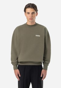 Khaki sweatshirt with a crew neck, cuffed sleeves, and ribbed hem. Features a small white "PEGADOR" logo on the chest. Soft texture.