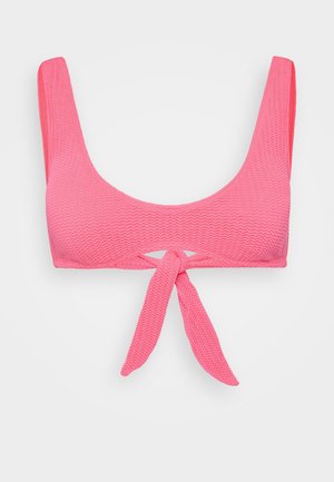 Rožinė bikini viršutinė dalis su tekstūruotu paviršiumi, kvadratiniu iškirpimu ir plačiomis petnešėlėmis. Yra priekinis raištelis ir išpjova centre.