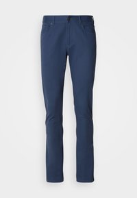 Granatowe spodnie wykonane z bawełny o gładkiej fakturze. Posiadają zapięcie na guzik, szlufki na pasek oraz dwie przednie kieszenie. Slim fit.