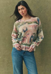 Gebreide trui met een multicolor patroon in roze, groen en blauw. Losse pasvorm met geribde manchetten en zoom, textuurdesign. Gecombineerd met blauwe jeans.