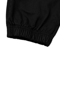 Schwarze Jogginghose mit elastischem Bund und glatter Stoffoberfläche. Der Saum ist gerafft für einen engen Sitz.