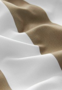 Stoff mit abwechselnd breiten Streifen in Weiß und Hellbraun, mit glatter Textur und leichtem Glanz, die sanfte Wellen erzeugen.