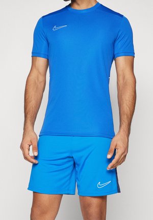 Mann trägt hellblaue Nike-Sportbekleidung mit kurzärmeligem Shirt und passenden Shorts mit weißen Nike-Logos.