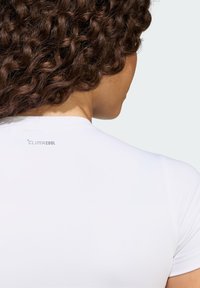 Biele športové tričko s hladkým povrchom a okrúhlym výstrihom, s logom "CLIMACOOL" potlačeným na zadnej strane.